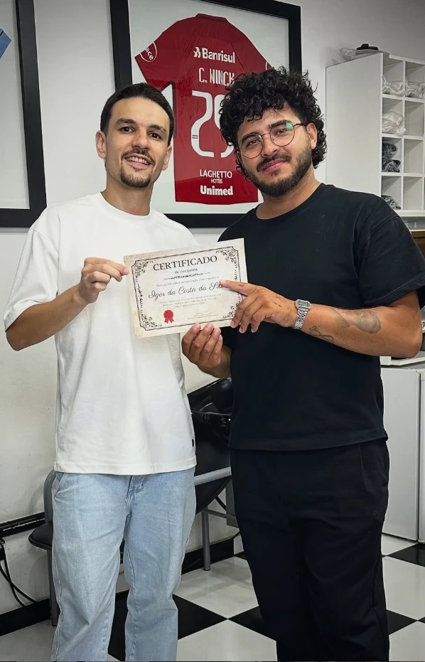 Rodrigo Dullius entregando o certificado de conclusão do curso Barbeiro 360° a um novo barbeiro