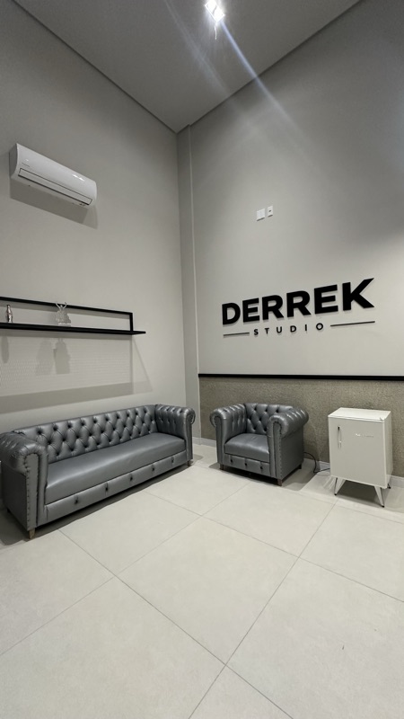 Recepção com sofás de couro e letreiro DERREK